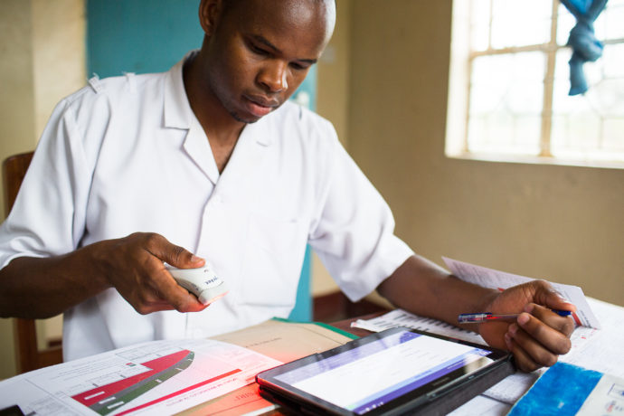 Photo: PATH/Trevor Snapp. Paulo Urioh scans a child health card into the new electronic immunization system at rural Mareu Health Center in Tanzania as part of the BID Initiative.